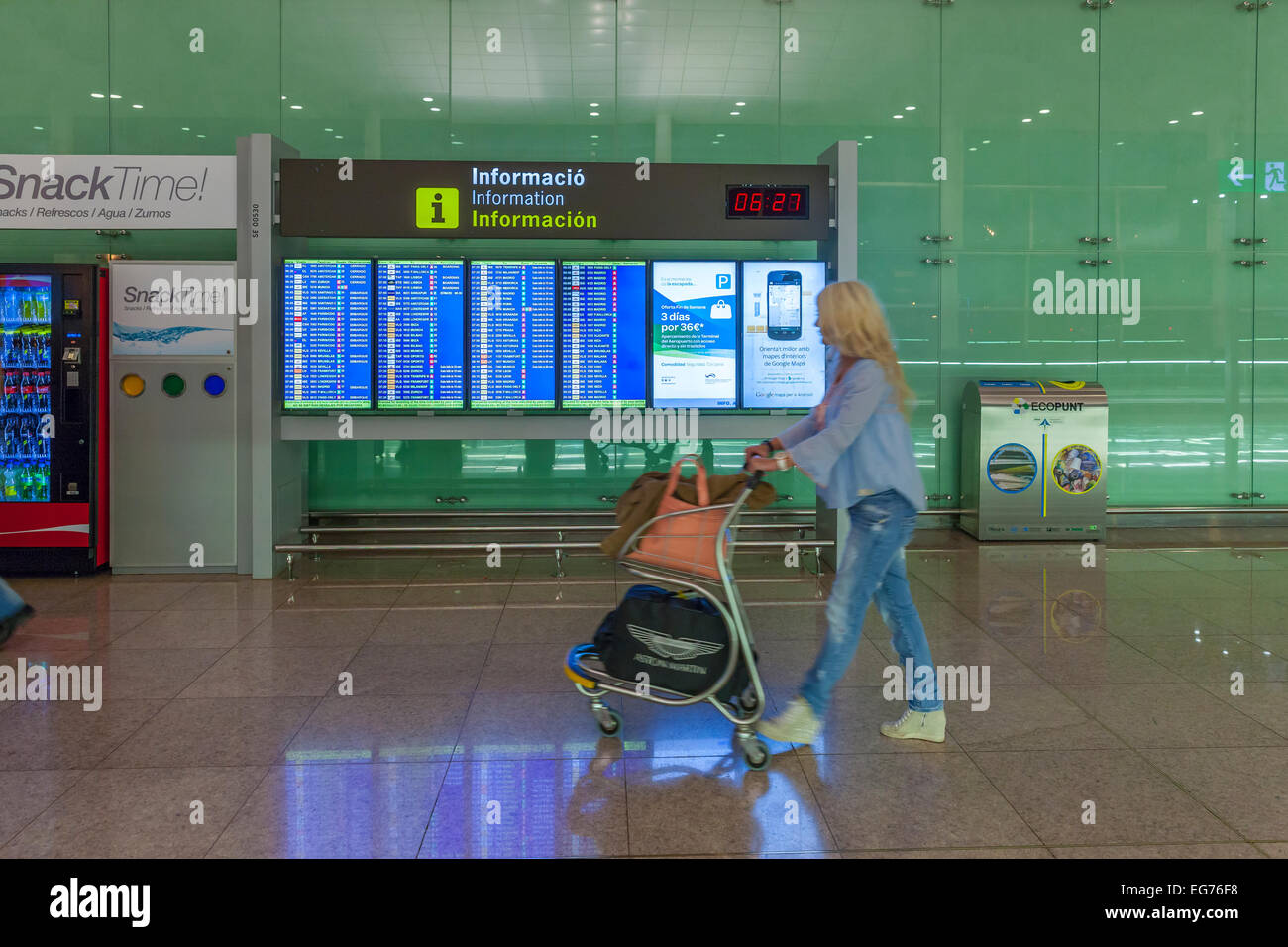 Spagna Isole Canarie Lanzarote, Arrecife, donna spingendo il carrello bagagli nella parte anteriore del pannello di visualizzazione all'aeroporto Foto Stock
