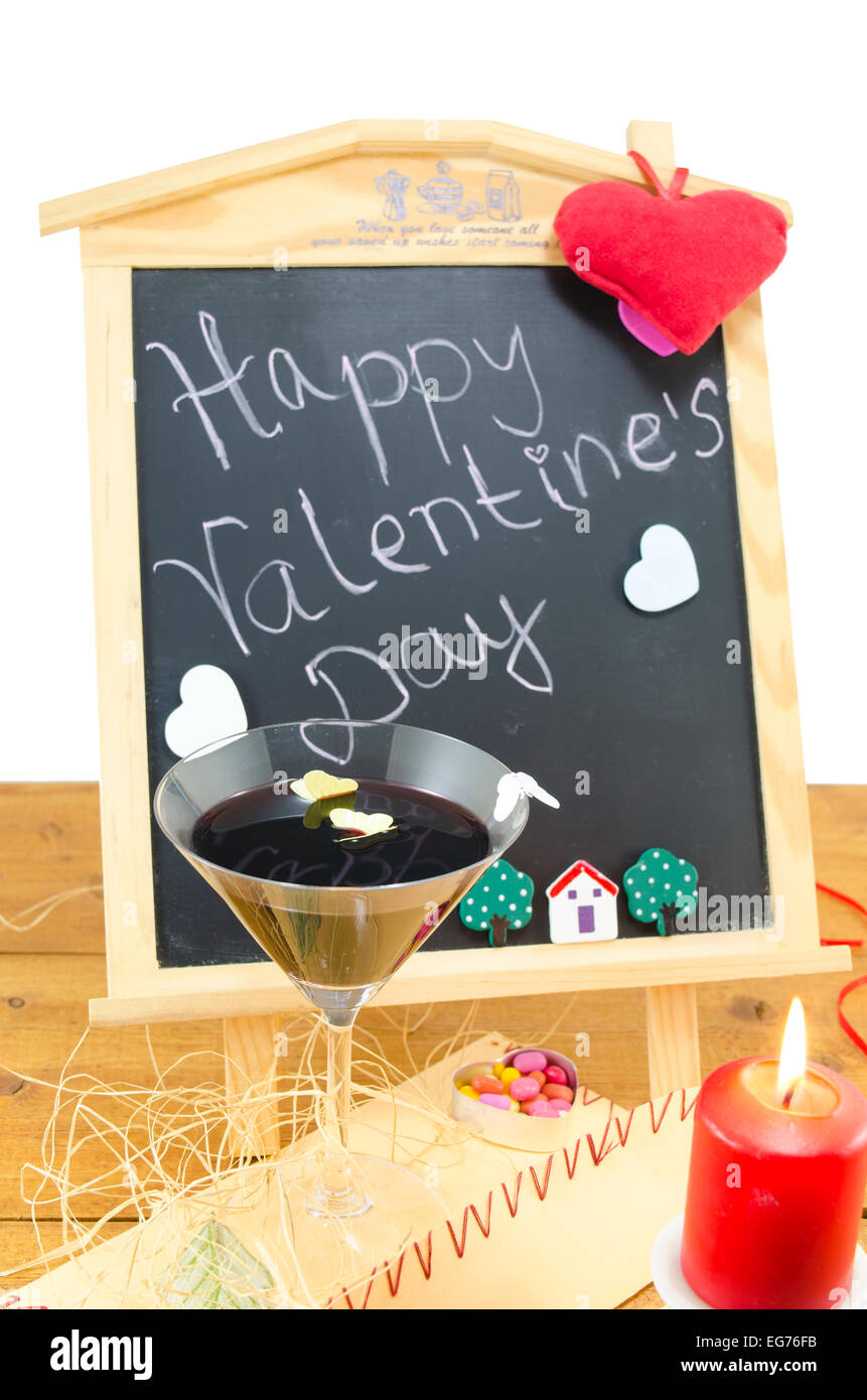 Lavagna a fogli mobili con le parole Happy Valentines scritto su di esso, decorata con cuori, una candela e un bicchiere di vino Foto Stock