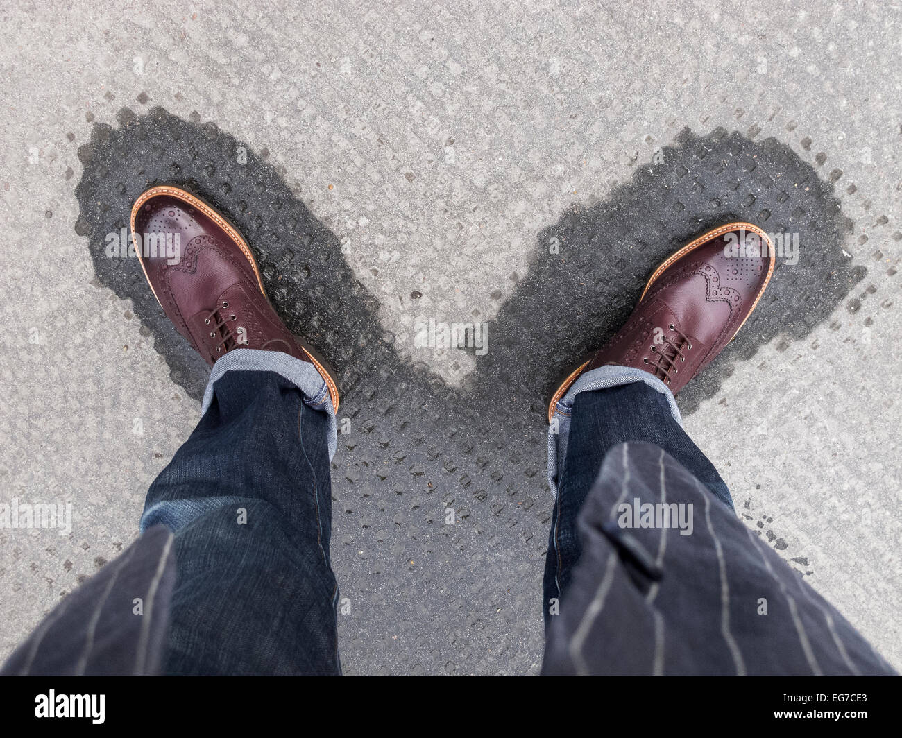 Un Uomo in camicia, jeans e un paio di stivali brogue in piedi sul bagnato  segna su un marciapiede Foto stock - Alamy