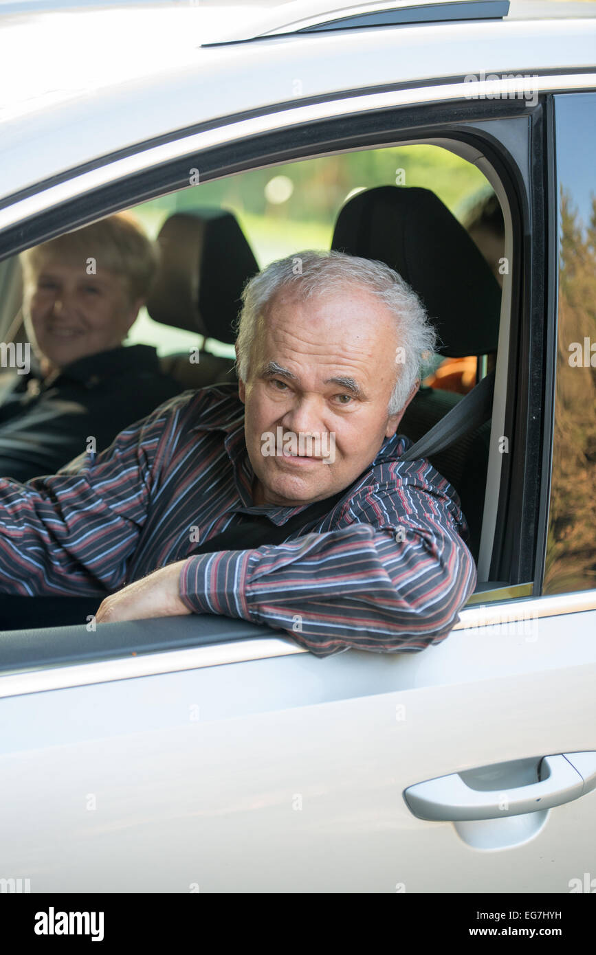 Senior uomo alla guida di una vettura, femmina senior passeggero seduto in macchina Foto Stock