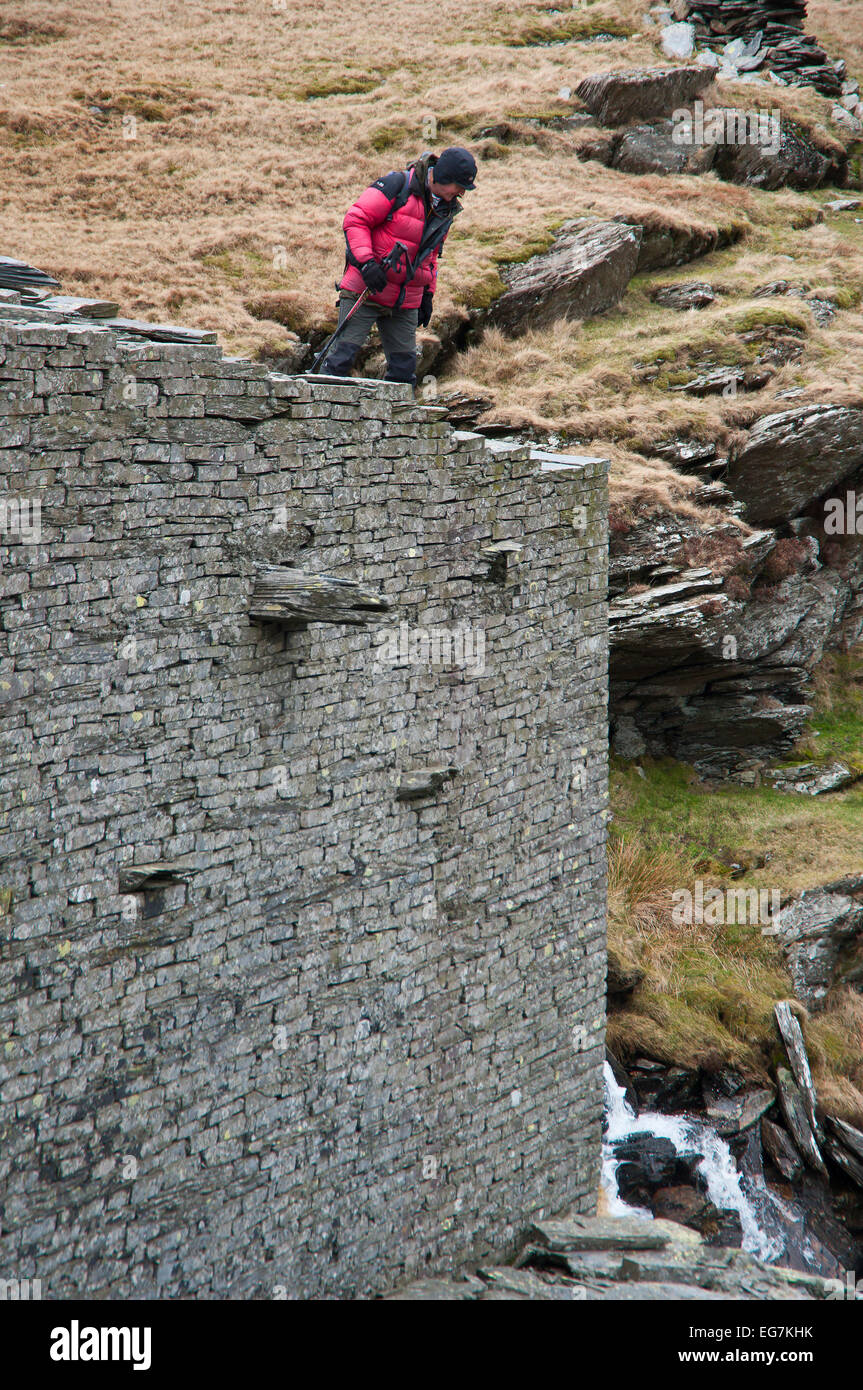 Parco Nazionale di Snowdonia, Gwynedd, Wales, Regno Unito. 17 Febbraio, 2015. Un escursionista visiti il abbandonato Rhosydd cava di ardesia come parte dei suoi giorni tour a piedi. Rhosydd cave di ardesia è iniziata nel 1840 e impiegato 200 uomini al suo picco nel 1880 quando oltre 6 mila tonnellate di ardesia vendibile di un anno è stata prodotta. La escavazione continuò fino agli anni cinquanta ma non si è mai ripresa dopo il 'Grande caduta' nel 1900, una catastrofe che ha distrutto gran parte delle più redditizie si riserva. Credito: Graham M. Lawrence/Alamy Live News. Foto Stock