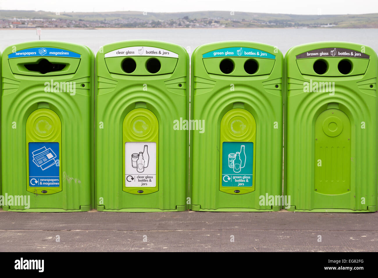 Set di bidoni di riciclaggio verde sul lungomare, Weymouth, Dorset, Inghilterra. Guidando a casa il messaggio che tutti abbiamo bisogno di riciclare il più possibile Foto Stock