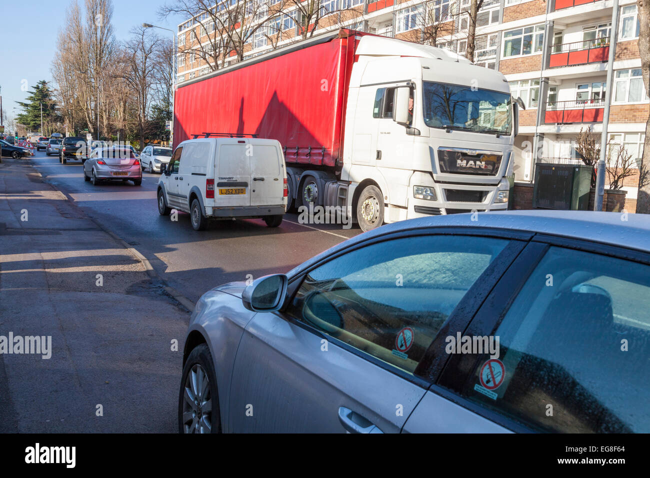 Auto parcheggiate sulla pavimentazione di una strada trafficata con traffico pesante in una zona residenziale. West Bridgford, Nottinghamshire, England, Regno Unito Foto Stock