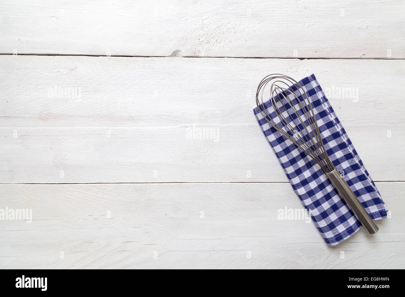Asciugamano da cucina e una frusta di luce su uno sfondo di legno Foto Stock