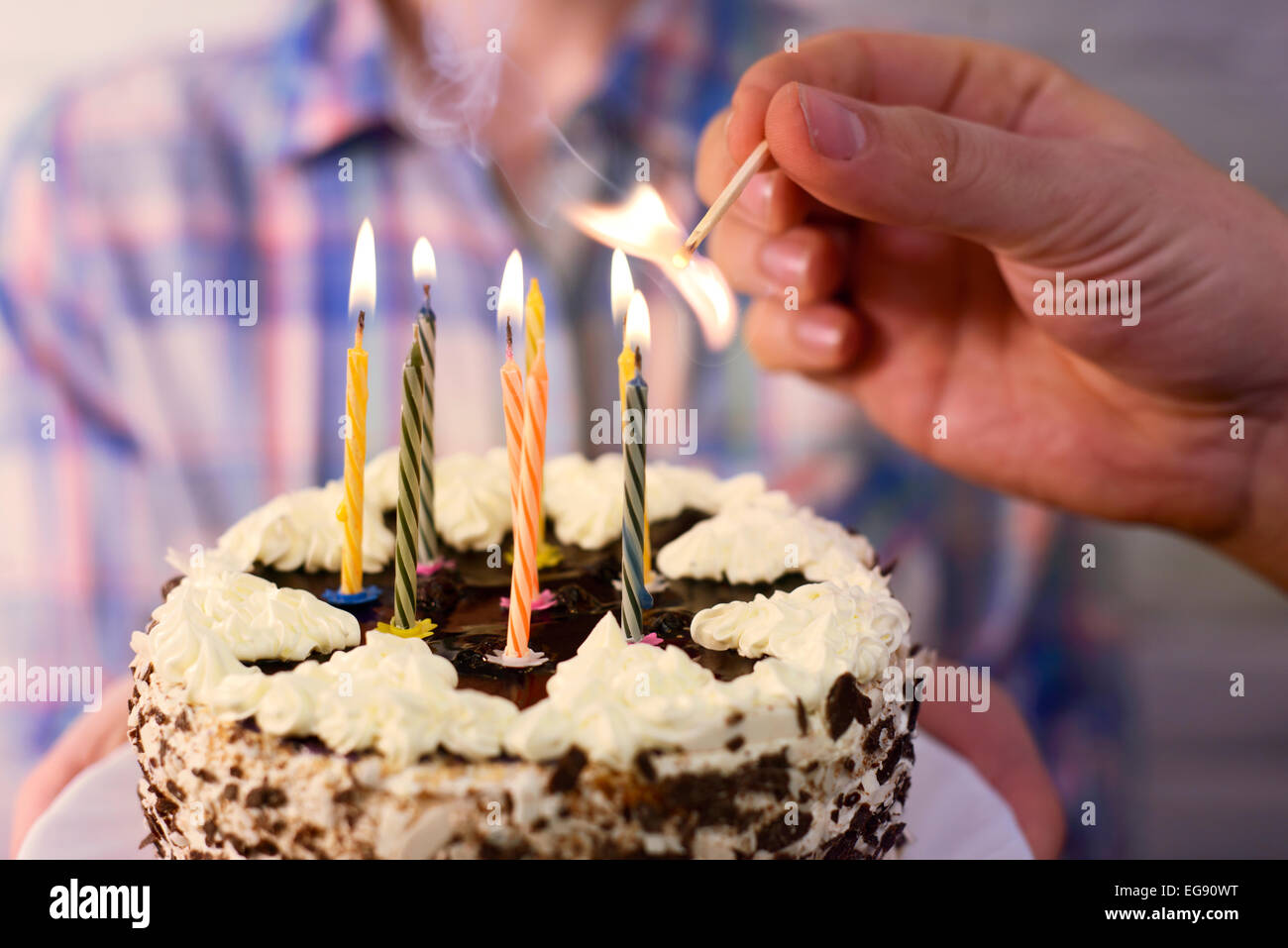 Maschio luci a mano le candeline sulla torta di compleanno Foto Stock