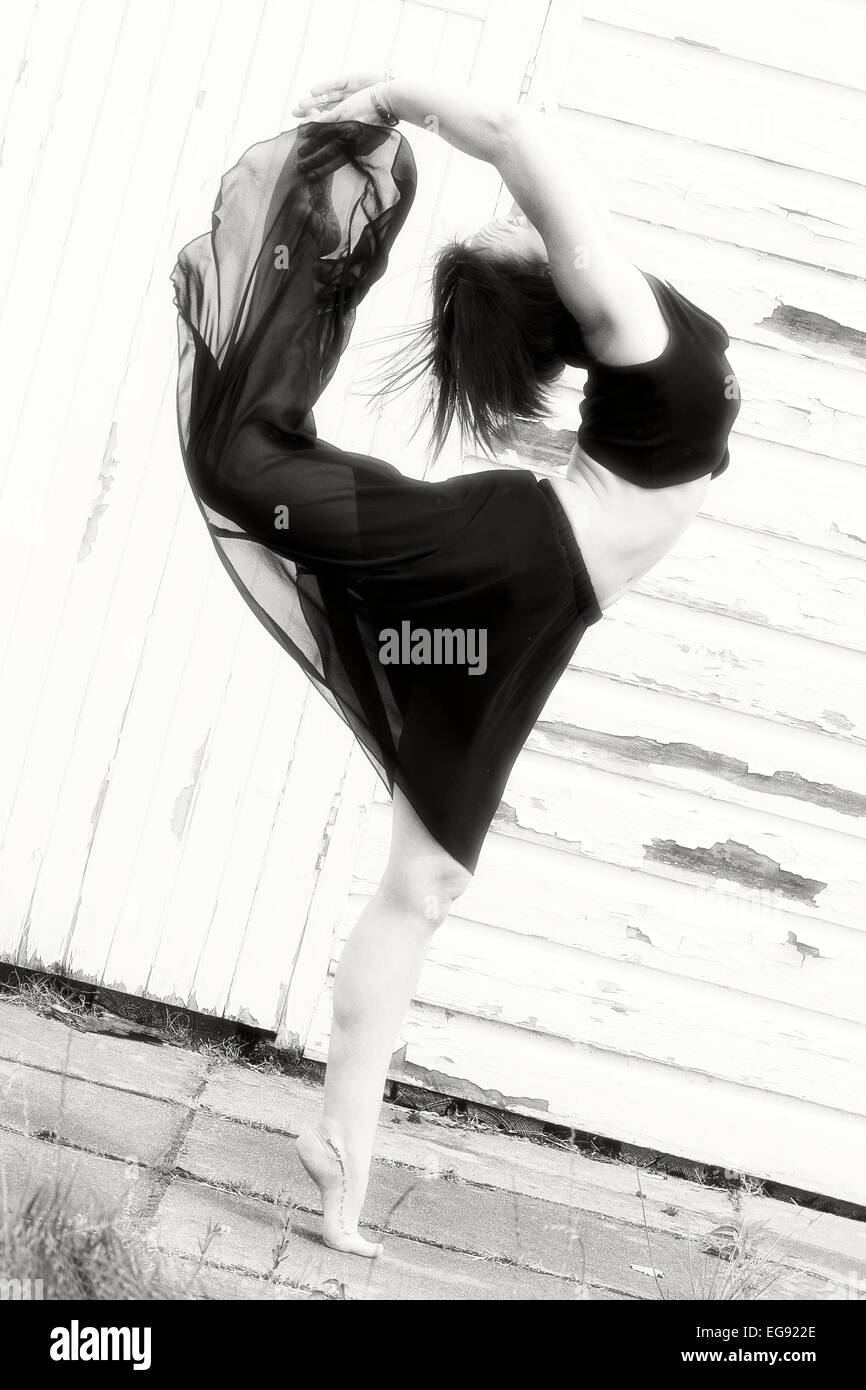 Ballerino femmina si riscalda al di fuori su lastre in calcestruzzo, di fronte a un capannone. Foto Stock