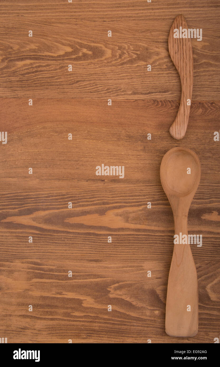 Il cucchiaio di legno e il coltello sul lato destro di legno scuro, configurazione tabletop, con copia spazio sulla sinistra Foto Stock
