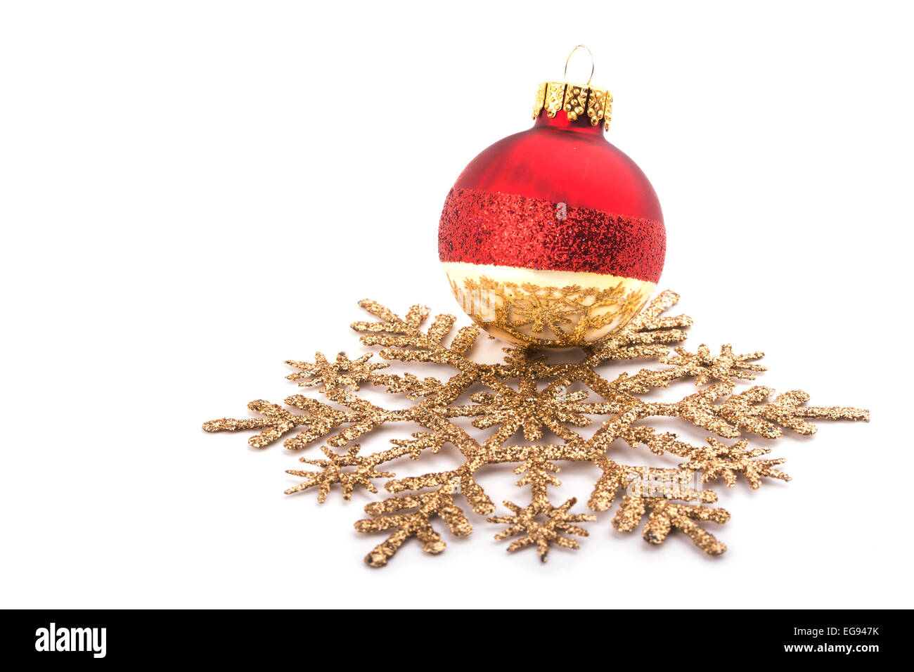 Pallina di natale ornamento in appoggio su un fiocco di neve dorata, focus sulla riflessione sulla pallina; con spazio di copia Foto Stock