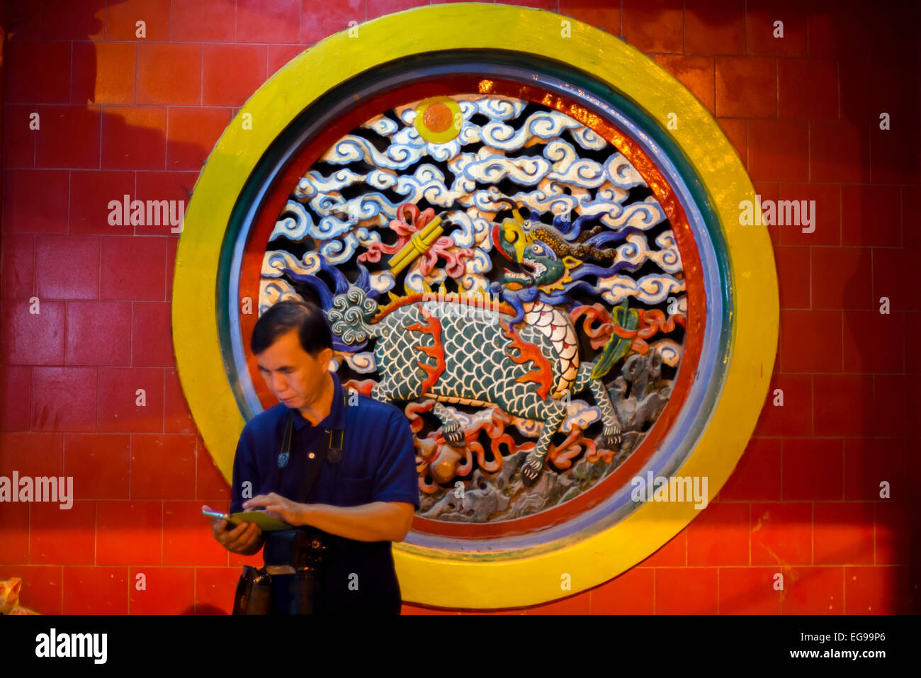Un uomo che si trova di fronte a una bella scultura a parete arrotondata al tempio Jin De Yuan, il più antico tempio cinese di Giacarta, Indonesia. Foto Stock