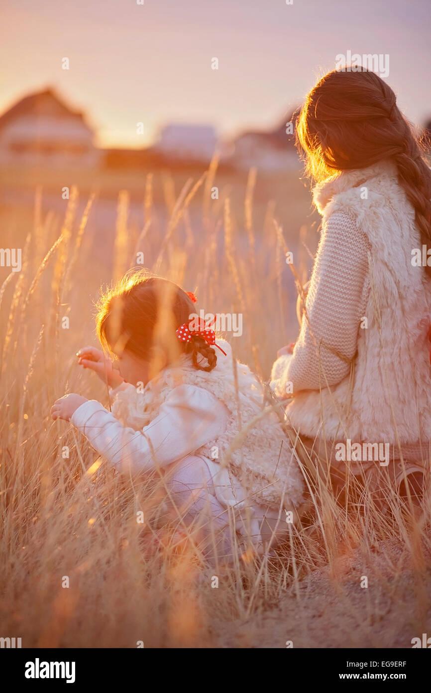 Due ragazze (2-3, 12-13) giocando fuori al tramonto Foto Stock