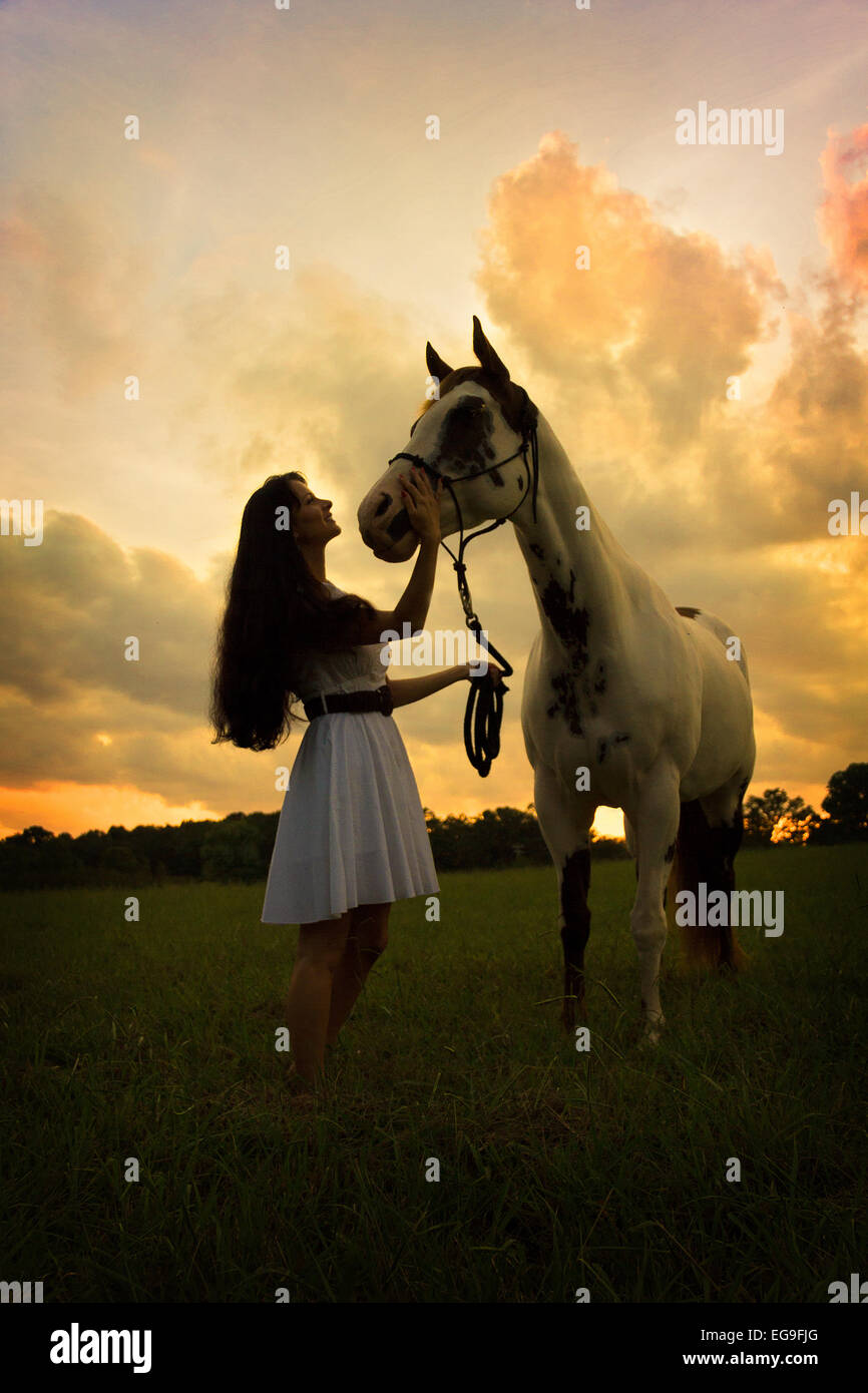 Donna con cavallo in campo al tramonto Foto Stock