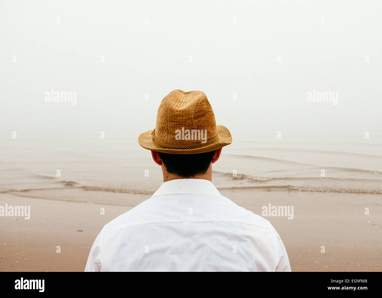 Uomo in cappello di paglia sulla spiaggia cercando di visualizzare Foto Stock