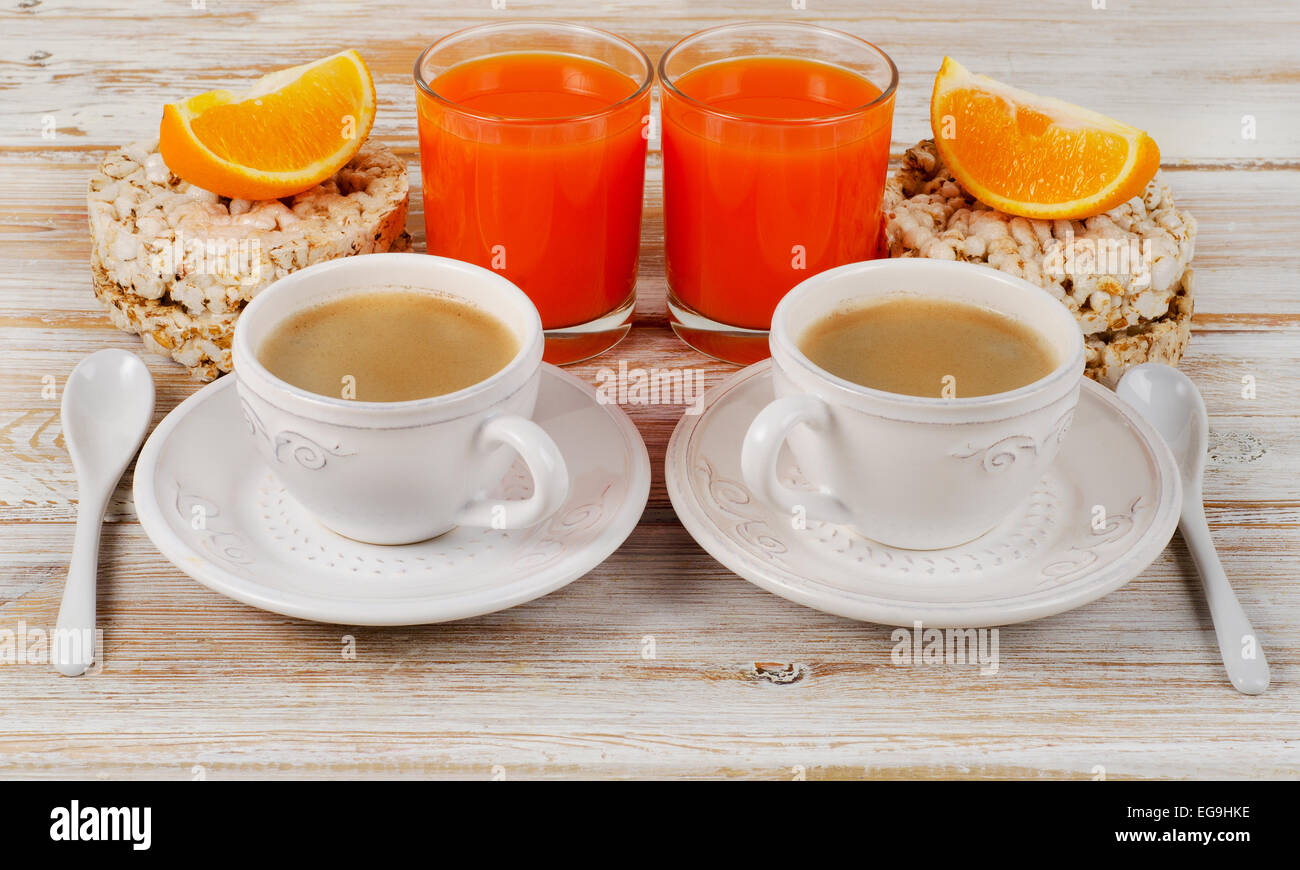 Sana colazione con due tazze di caffè, succo d'arancia sul tavolo di legno. Foto Stock