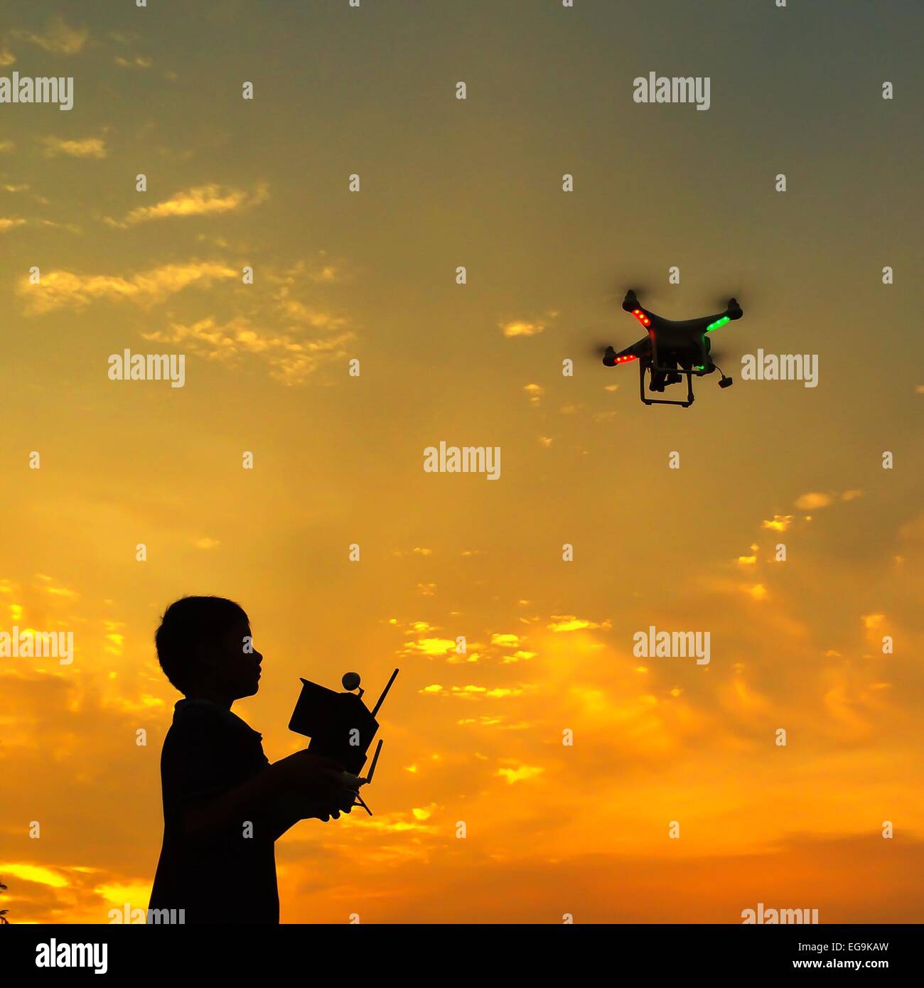 Silhouette di boy battenti un drone al tramonto Foto Stock