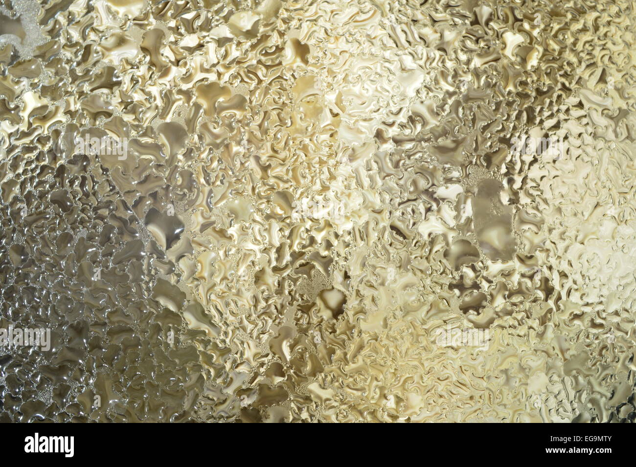 Abstract background. Golden gocce di acqua sul materiale di vetro. Foto Stock