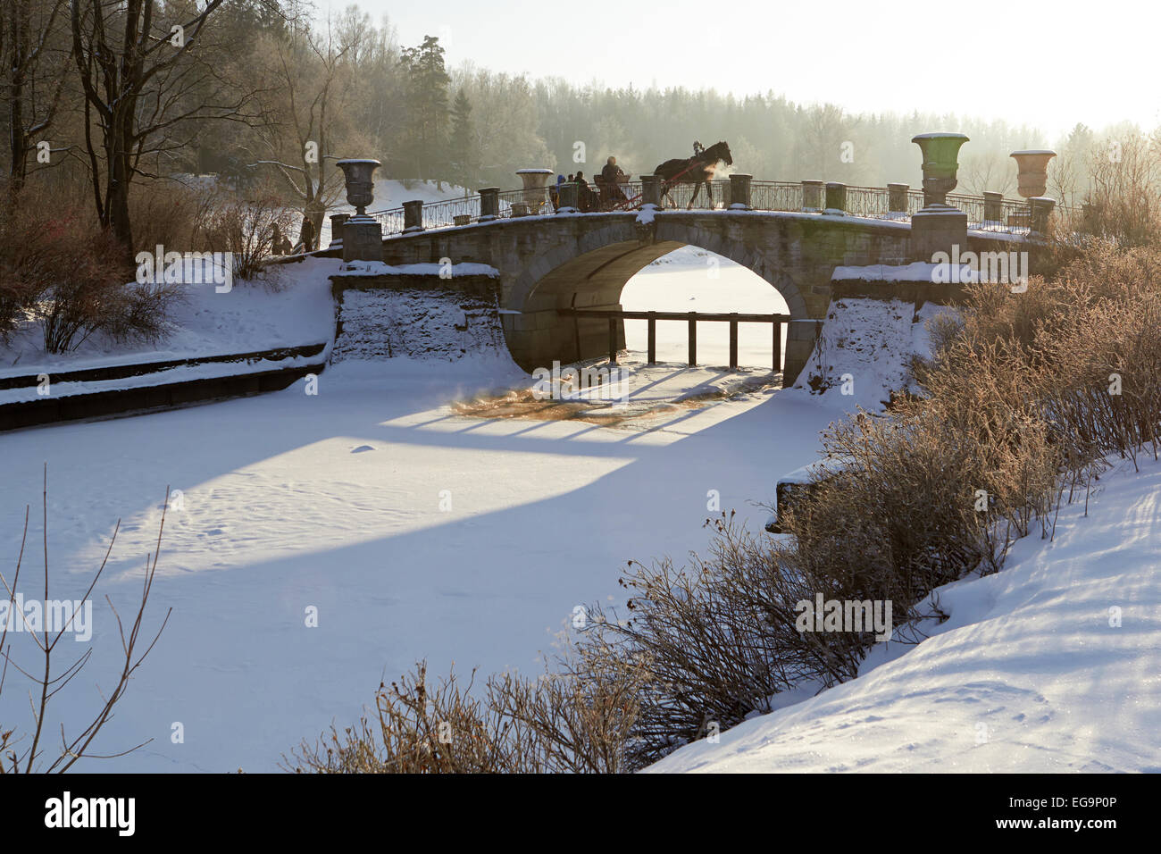 In inverno il paesaggio soleggiato con carrozza a cavalli sul ponte vecchio Foto Stock