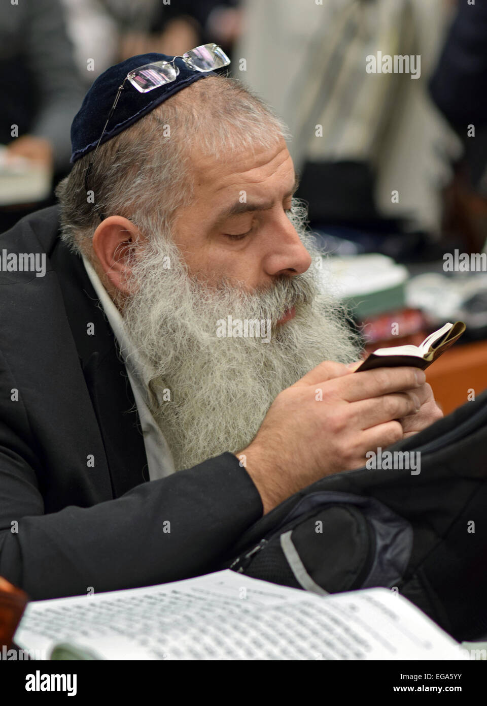 Una religiosa ebraica uomo la lettura da un piccolo libro ebraico in una sinagoga in Crown Heights, Brooklyn, New York City Foto Stock