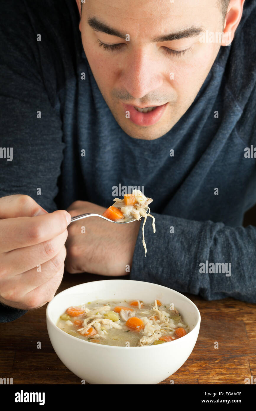 Uomo di mangiare in casa la zuppa di pollo Foto Stock