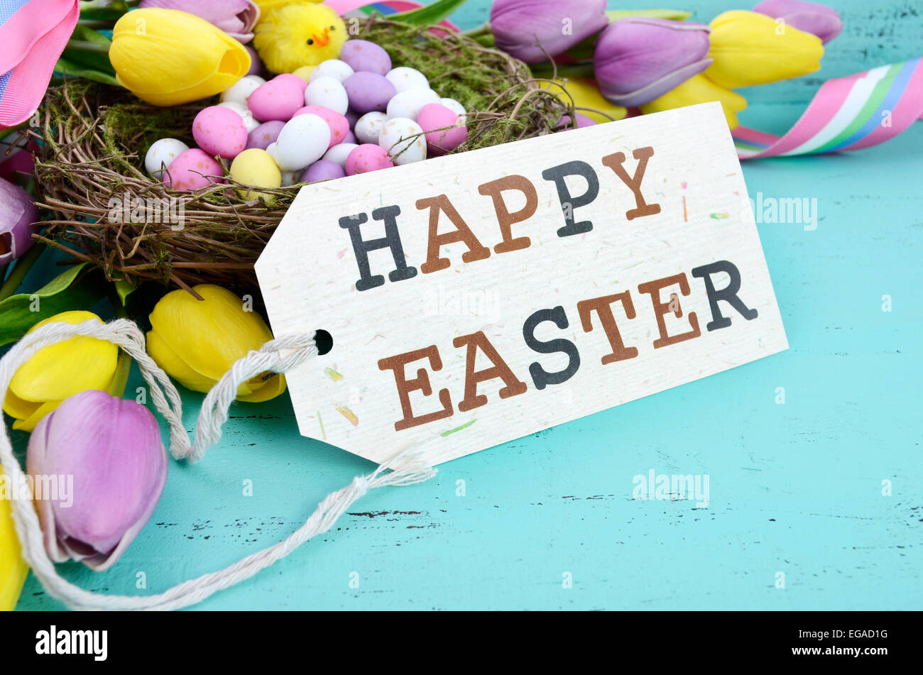 Felice Pasqua lo sfondo con il dipinto di uova di Pasqua nel nido di uccelli e giallo e viola i tulipani di seta e nastro su stile vintage ru Foto Stock