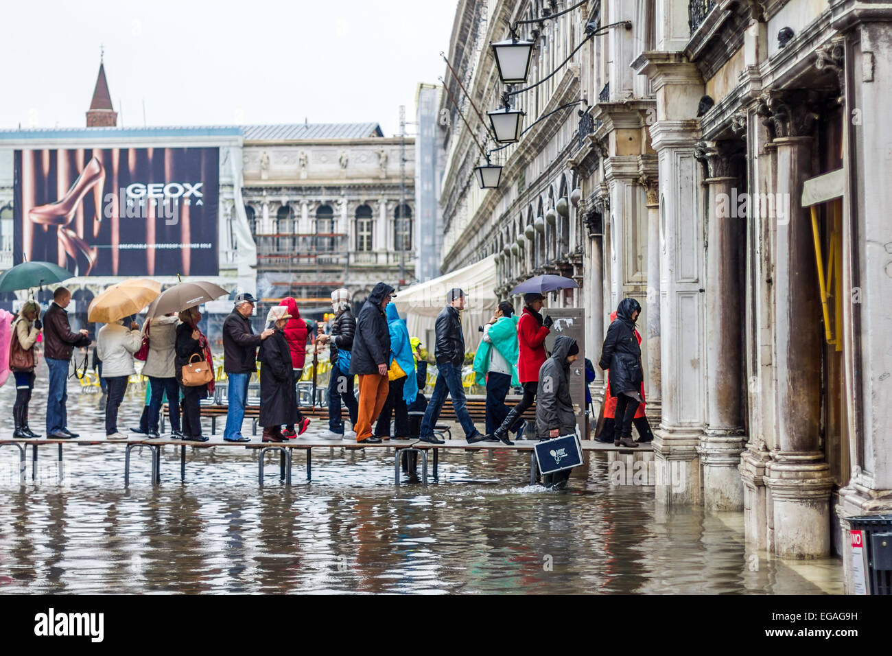 I turisti a piedi lungo percorsi sopraelevati durante le inondazioni (l'acqua alta in Piazza San Marco, Venezia Italia Foto Stock