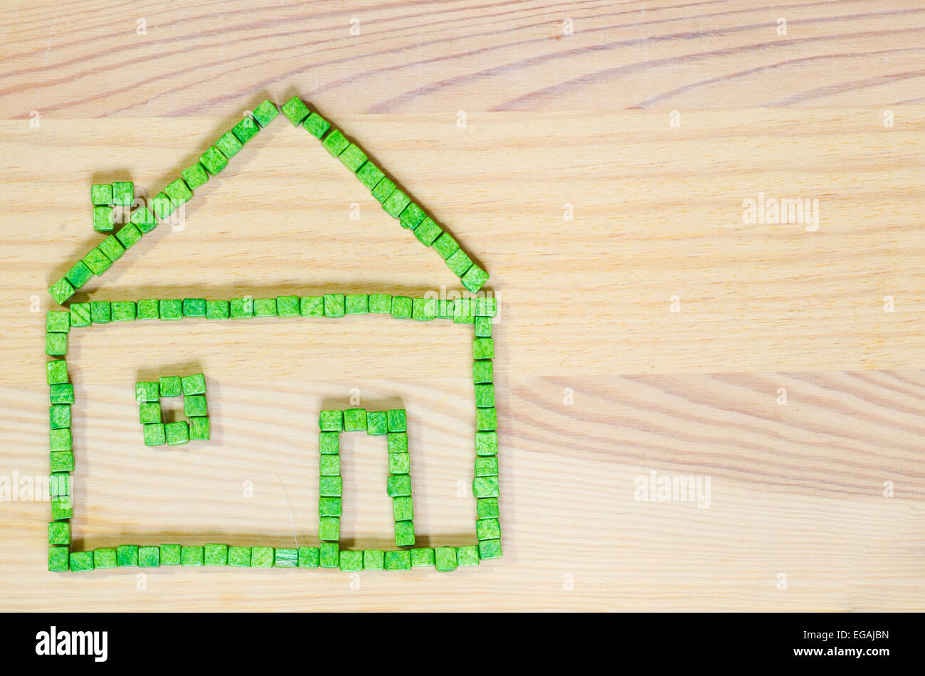 Casa verde realizzata con blocchi giocattolo su sfondo di legno Foto Stock