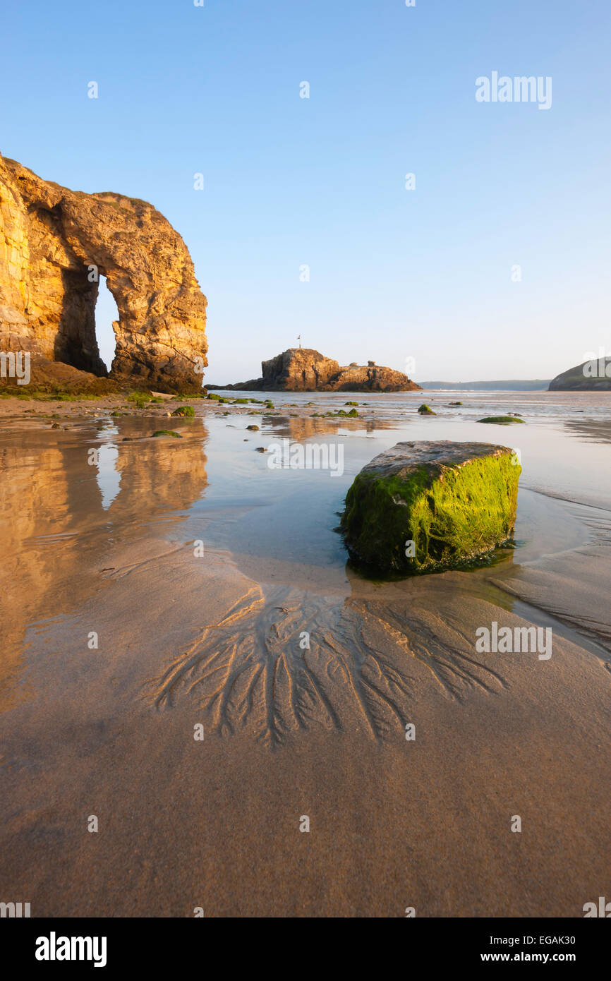 Perranporth spiaggia al tramonto su una chiara mattina mostra un grande arco nel terreno non lavorato riflettendo in acqua sulla sabbia. Foto Stock