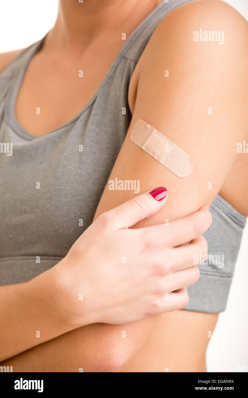 Donna del dolore con un bendaggio adesivo sul suo braccio Foto Stock