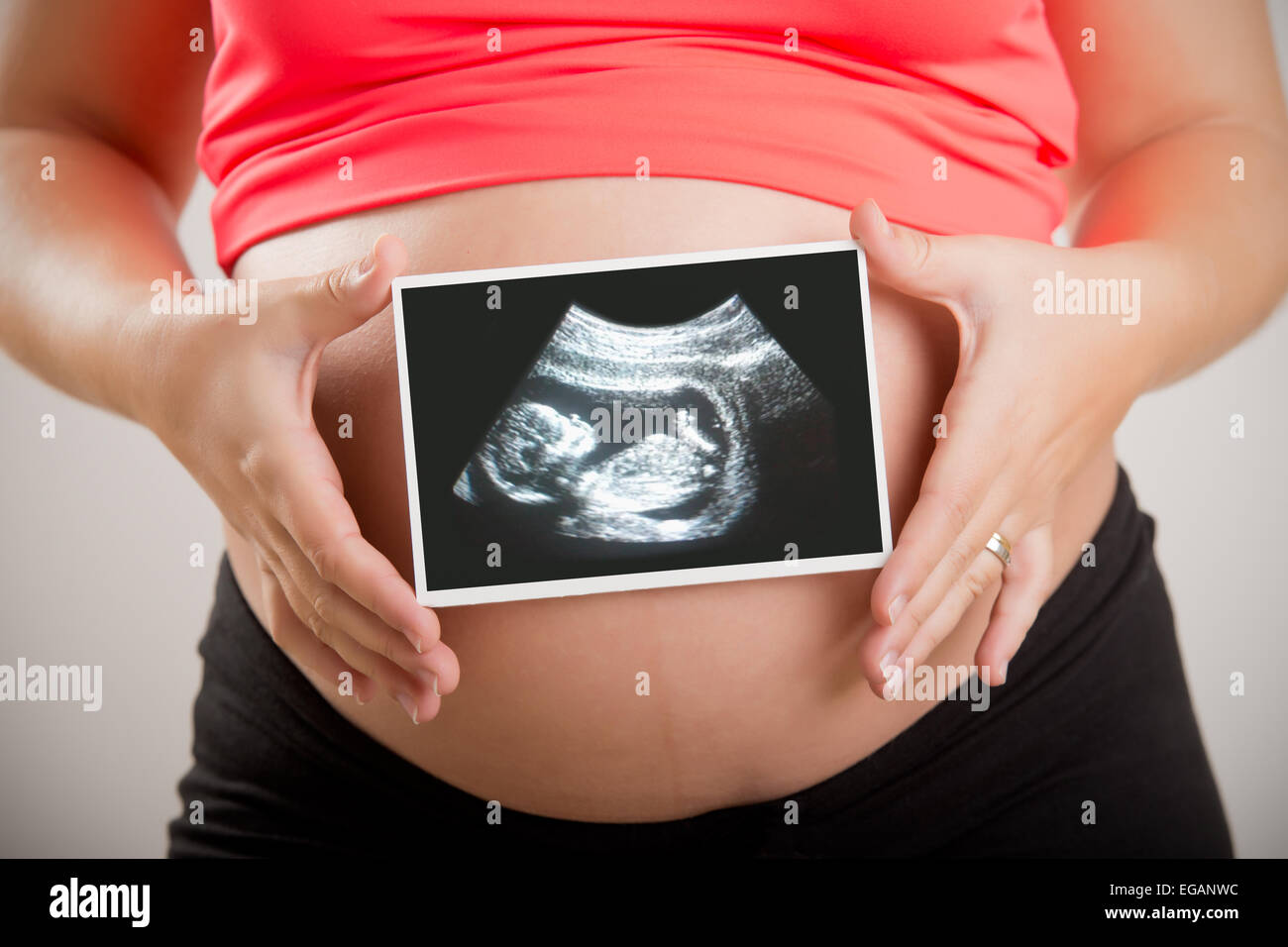 Donna che mantiene una scansione ad ultrasuoni del suo bambino non nato Foto Stock