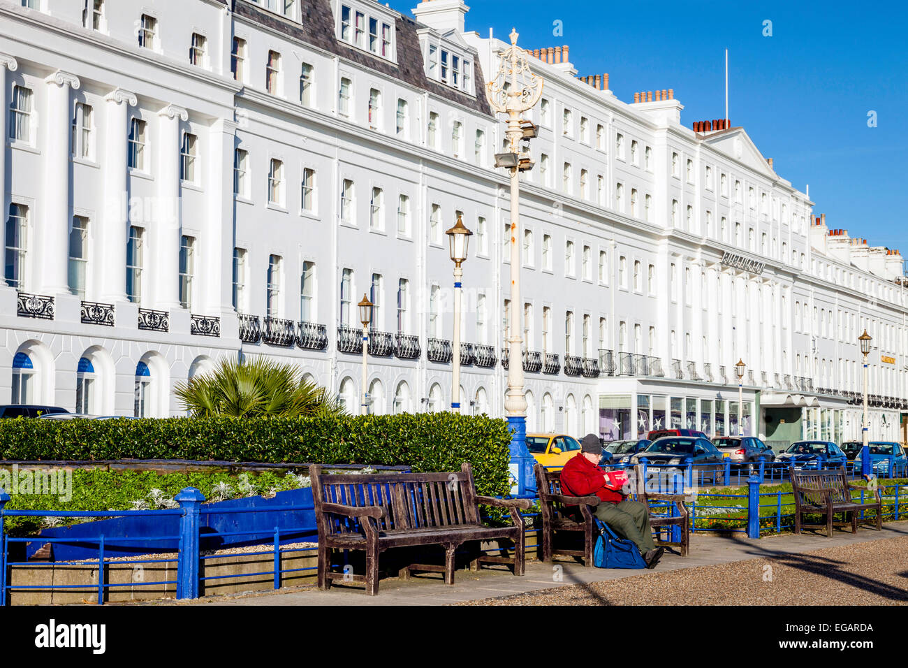 Un uomo si siede su una panchina a mangiare pesce e patatine, Eastbourne, Sussex, Inghilterra Foto Stock