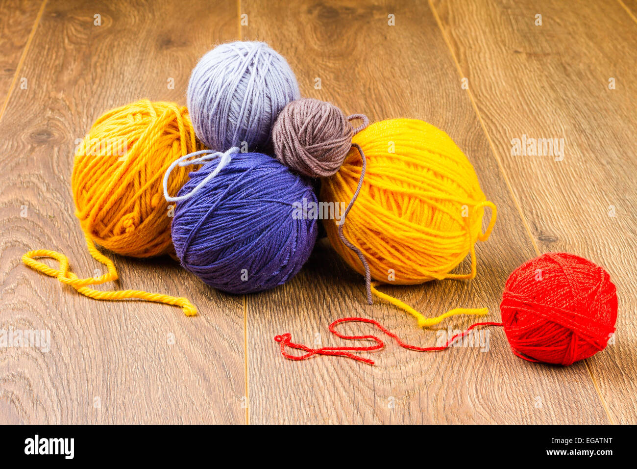 Giallo, blu scuro, lilla, marrone e il filo rosso su sfondo di legno Foto Stock