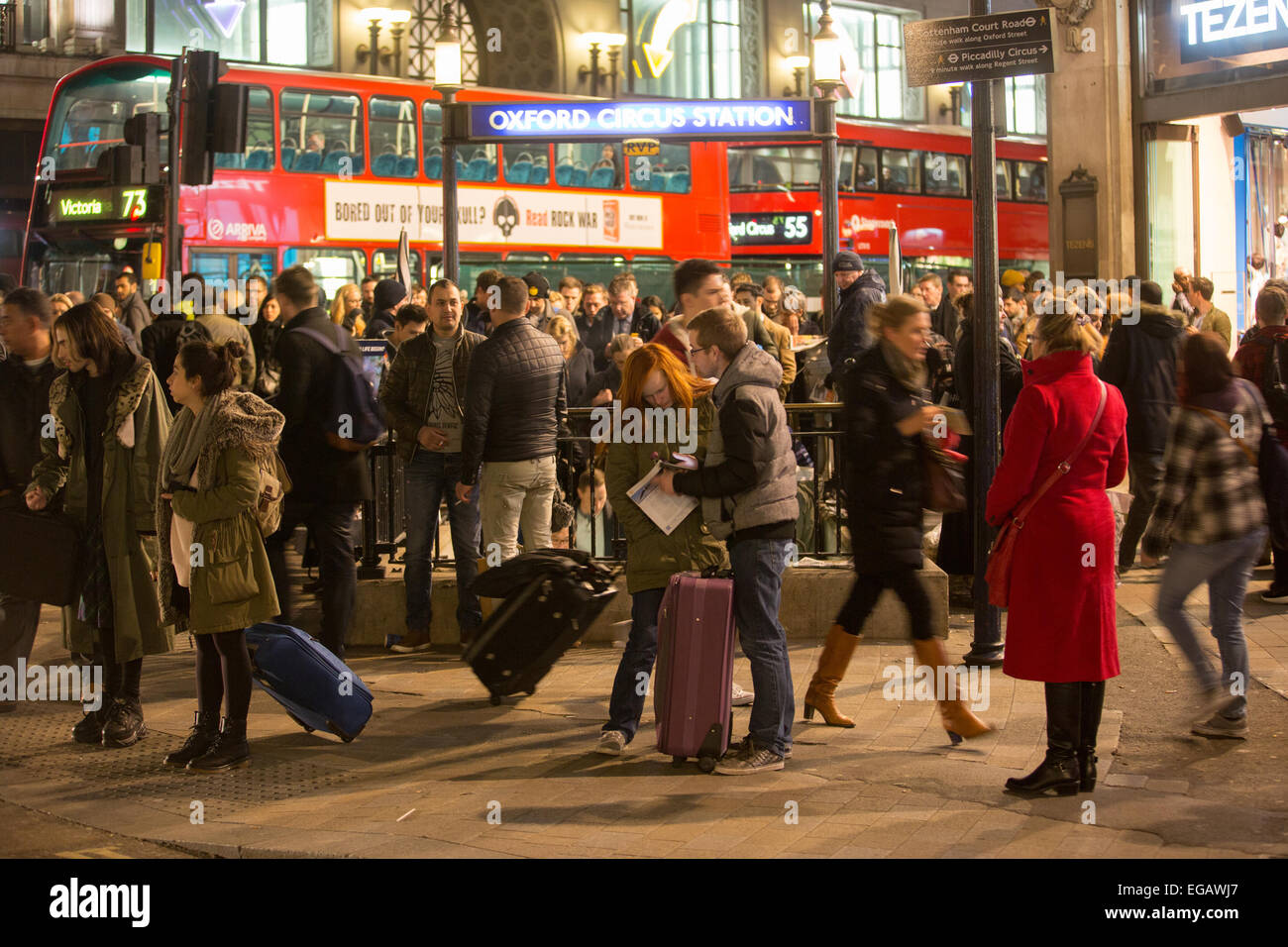 Una coppia consulti il loro telefono mobile mentre i pendolari ingannano dentro La metropolitana alla stazione di Oxford Street Foto Stock