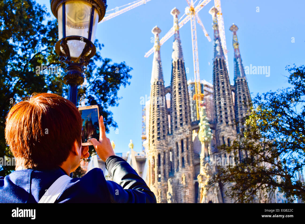 Turistica prendendo le foto con il suo cellulare. La Sagrada Familia di Barcellona, in Catalogna, Spagna. Foto Stock