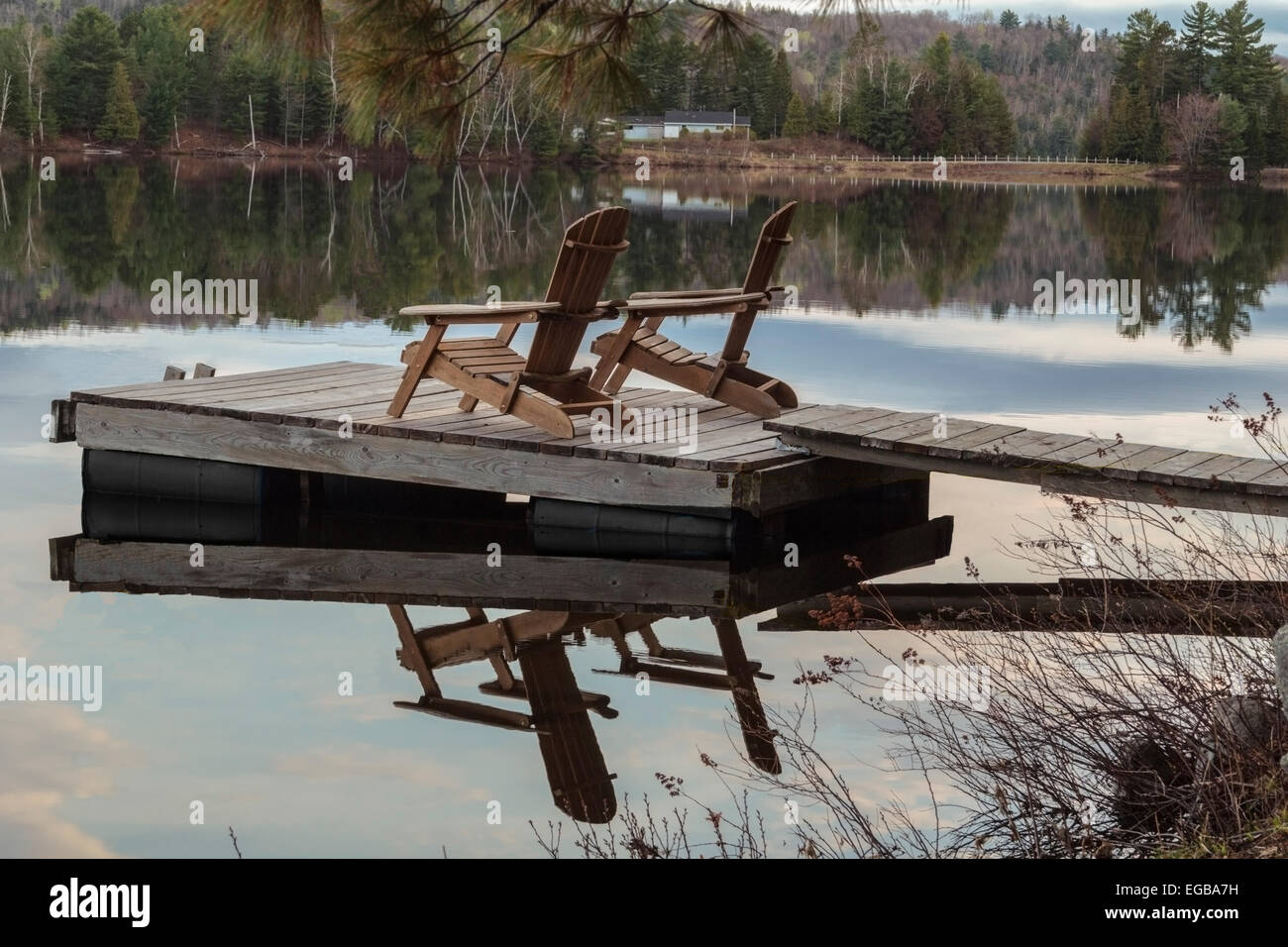 Scena pacifica di due reti a doghe a sedie a sdraio su una banchina in legno in un lago Ontario, Canada Foto Stock