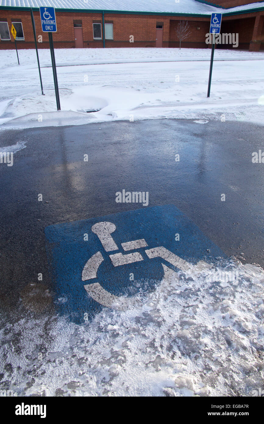 Handicap solo simbolo di parcheggio su terreni innevati parcheggio alla scuola elementare. Foto Stock