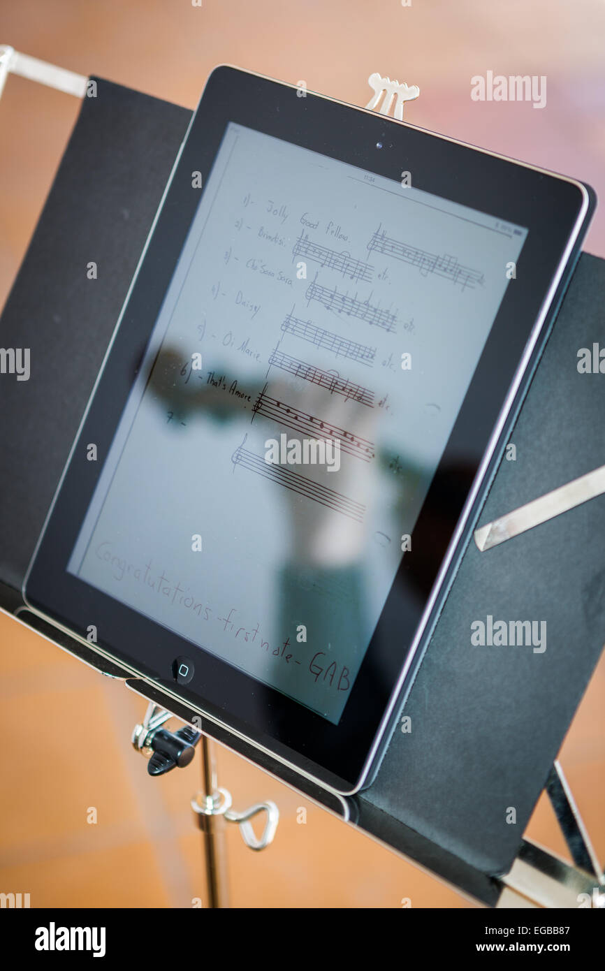 La riflessione su un ipad del violinista con il suo violino durante un matrimonio durante la lettura digitale di musica del foglio Foto Stock