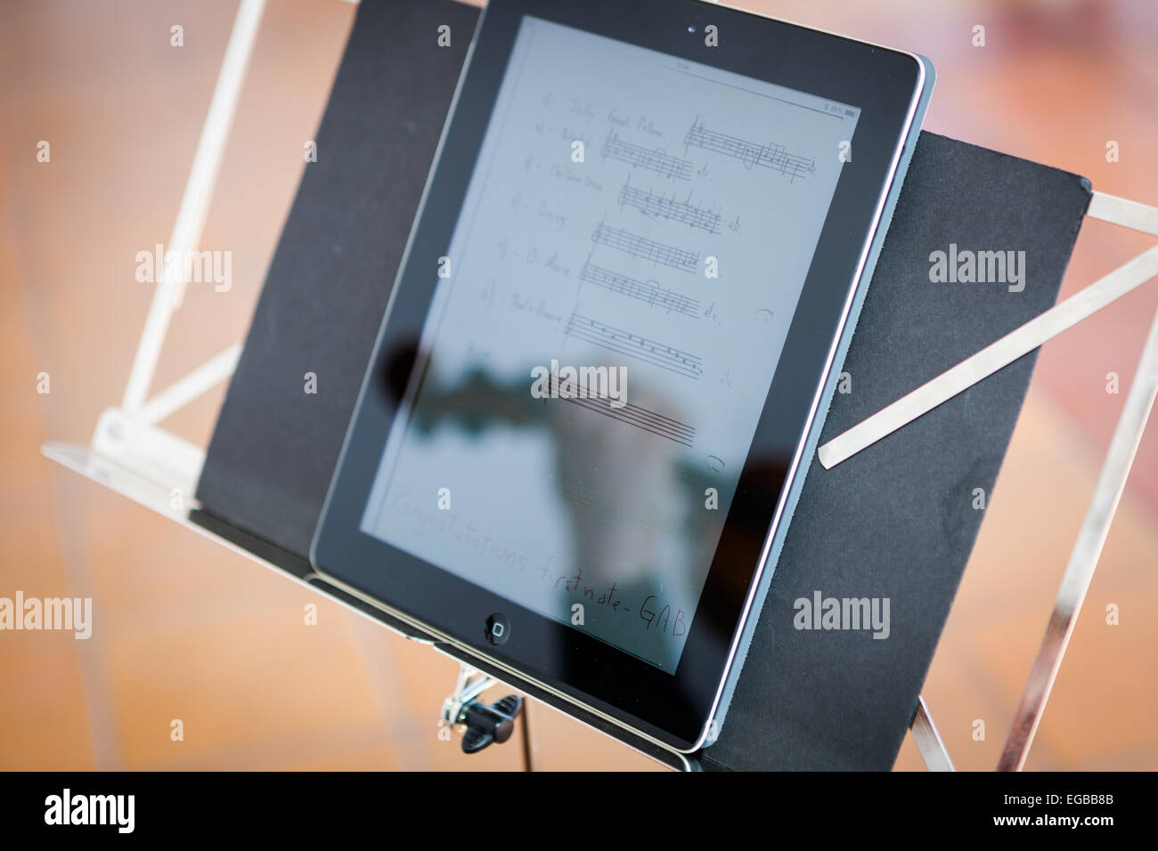 La riflessione su un ipad del violinista con il suo violino durante un matrimonio durante la lettura digitale di musica del foglio Foto Stock
