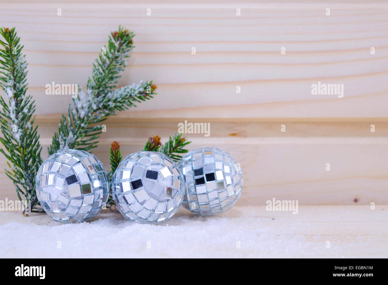 Tre discoteca ornamenti a sfera su una superficie in legno decorato con un ramo di abete Foto Stock