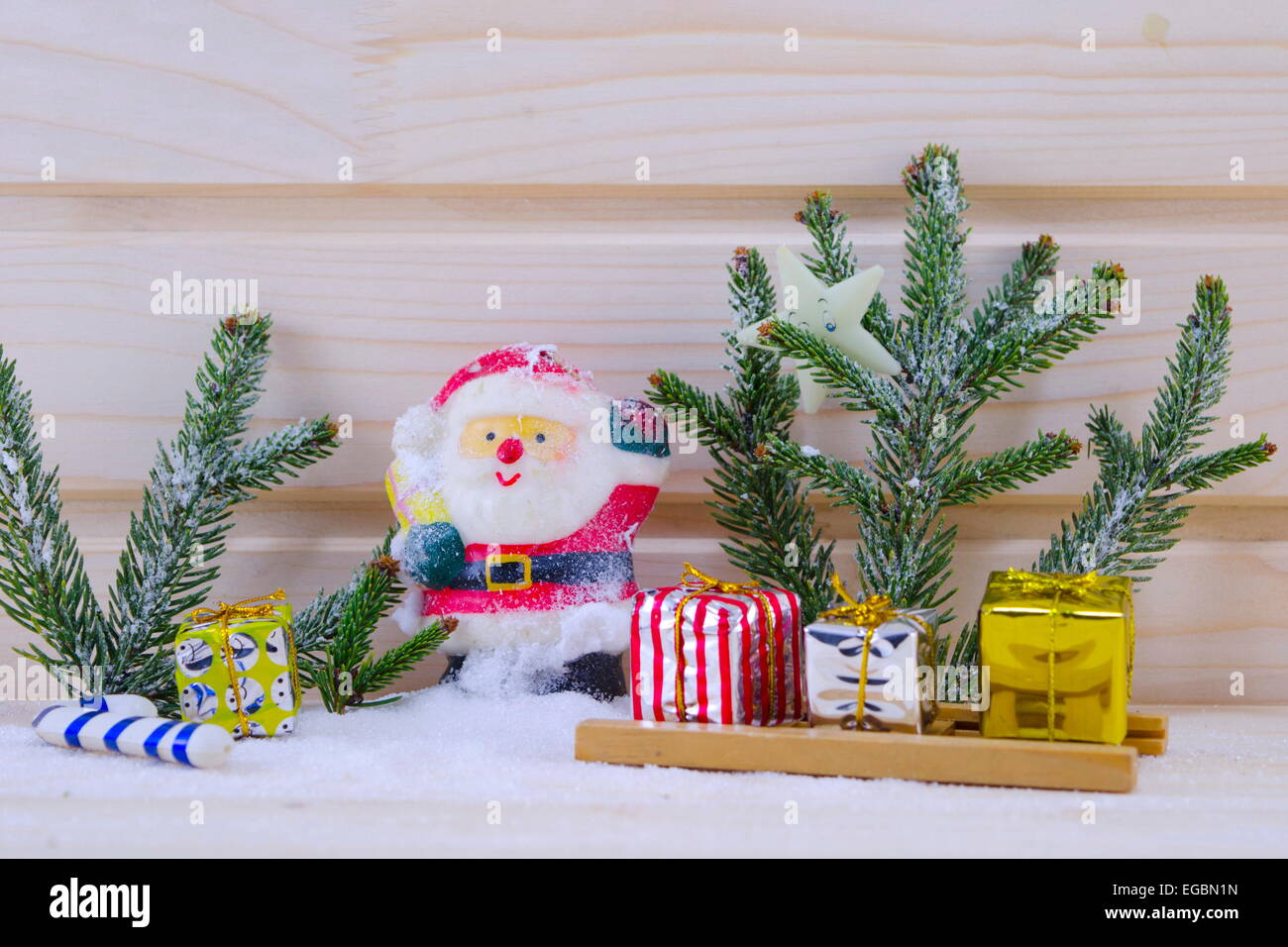 Toy Santa tra gli abeti e presenta su un nevoso superficie in legno Foto Stock