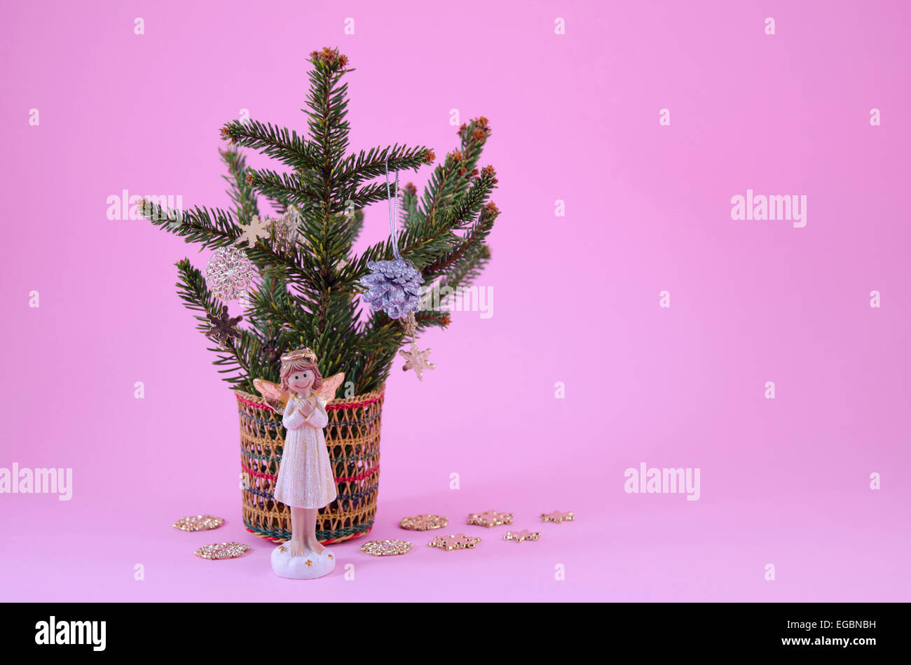 Angel figurine e un piccolo albero di Natale decorato con stelle e tiro su sfondo rosa Foto Stock