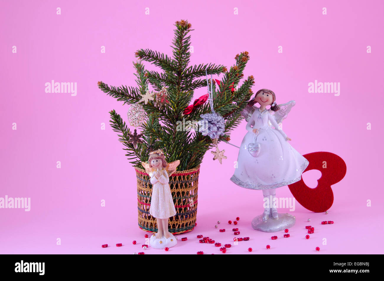 Due angeli figurine su sfondo rosa, decorato con stelle e un abete Foto Stock
