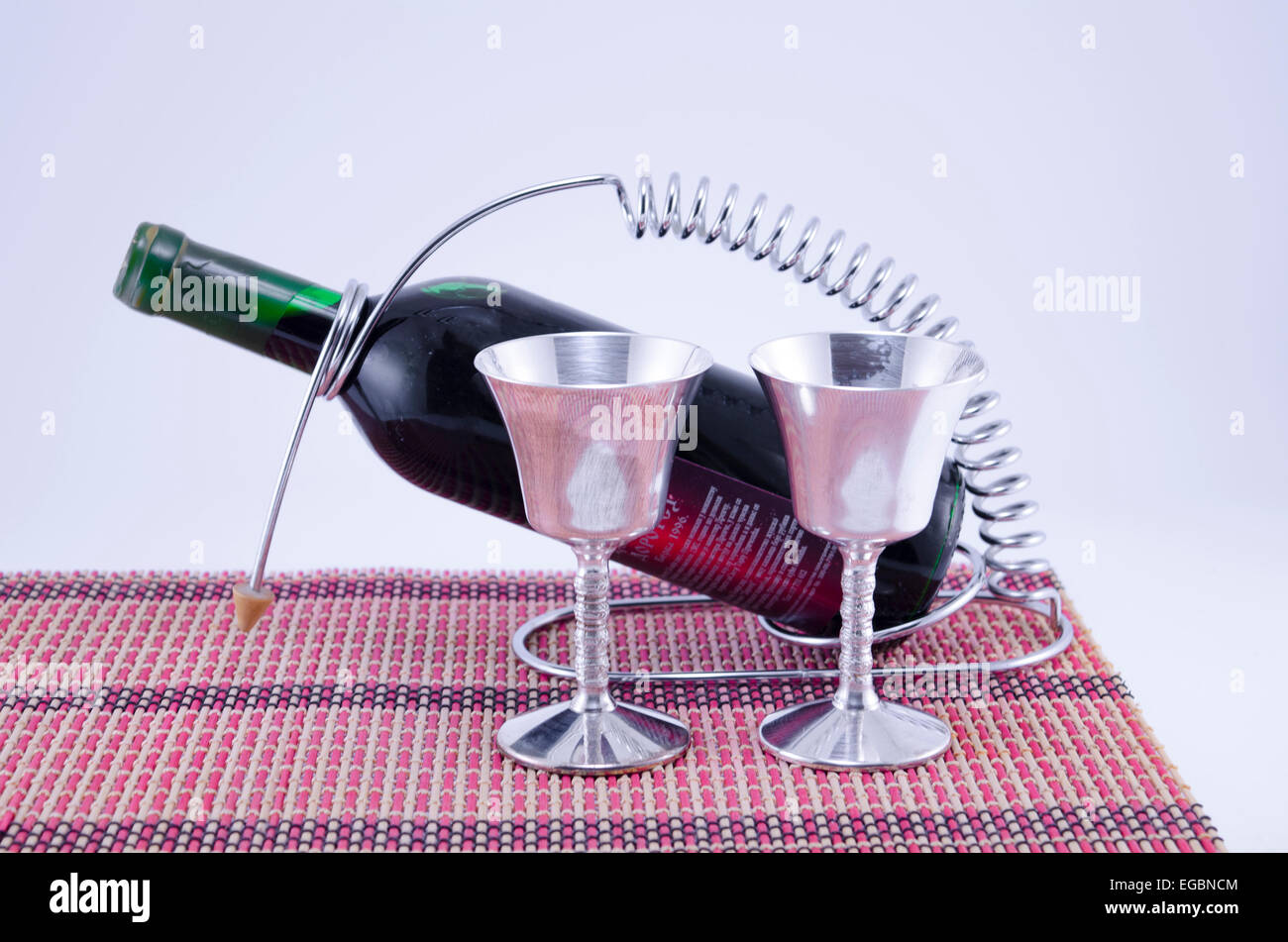 Due coppe d'argento e una bottiglia di vino sulla tovaglia Foto Stock