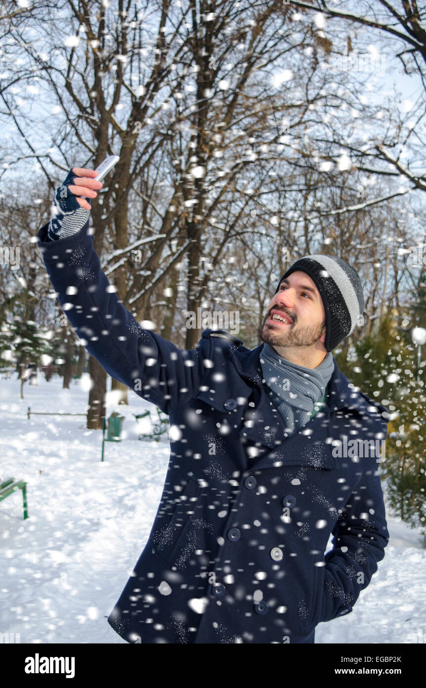 Uomo che parla un selfie mentre nevica in un parco Foto Stock