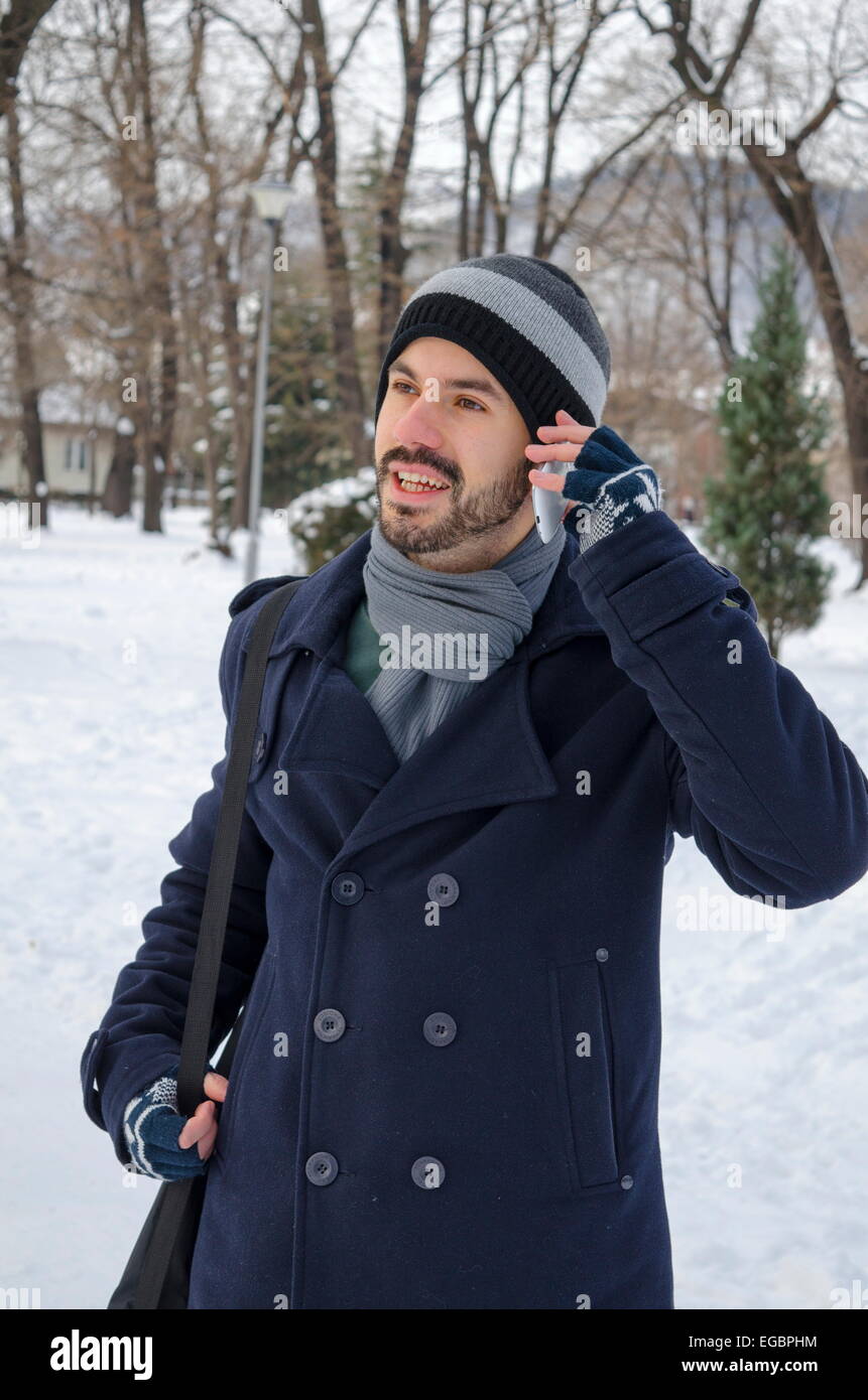 Uomo che parla su uno smartphone in inverno Foto Stock