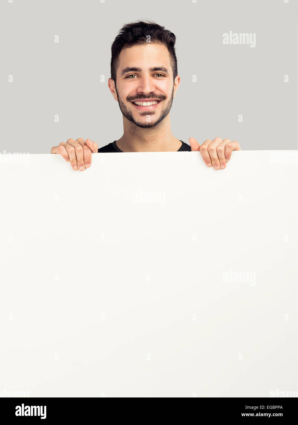 Bellissimo il latino uomo sorridente e trattenere uno sbozzato billboard Foto Stock