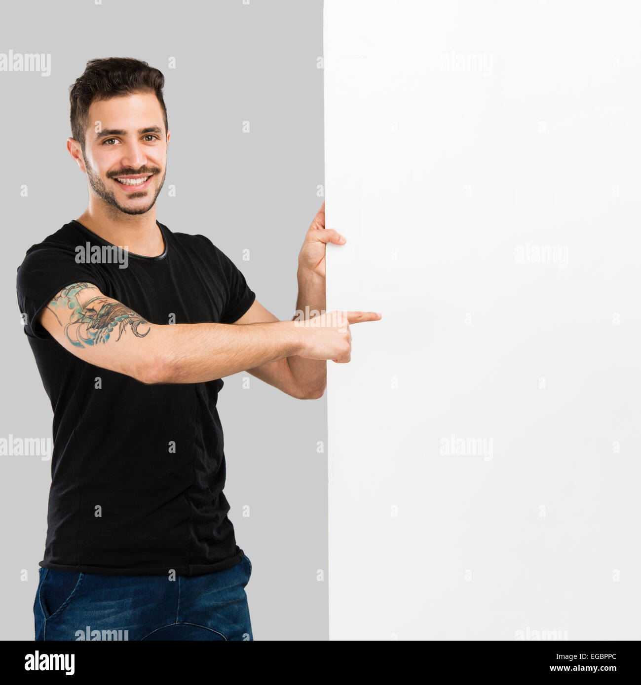 Bellissimo il latino uomo sorridente e puntando a un tabellone vuoto Foto Stock