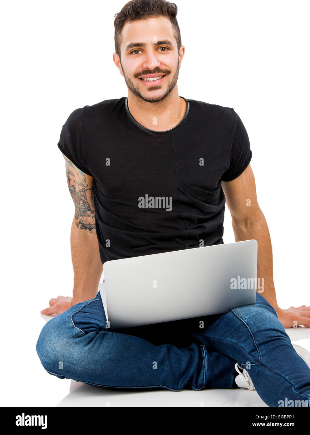 Latino uomo seduto sul pavimento e lavorare con un computer portatile Foto Stock