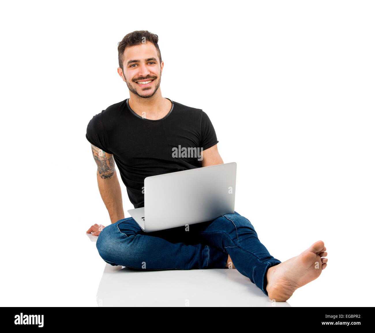 Latino uomo seduto sul pavimento e lavorare con un computer portatile Foto Stock