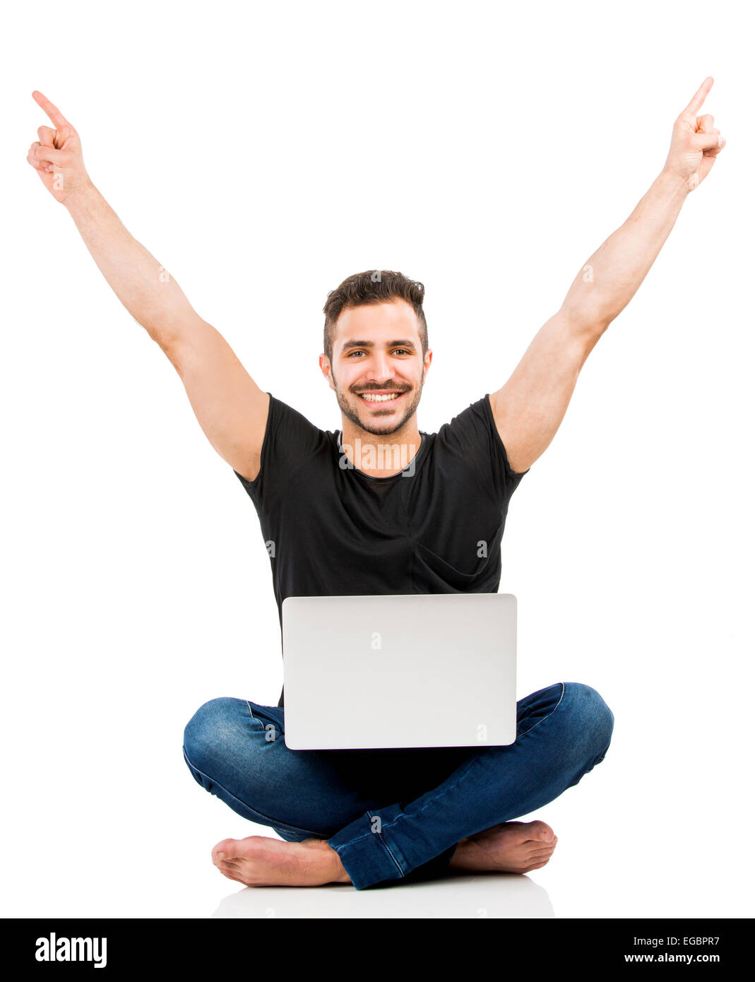 Latino uomo seduto sul pavimento e lavorare con un computer portatile con entrambe le braccia in alto Foto Stock