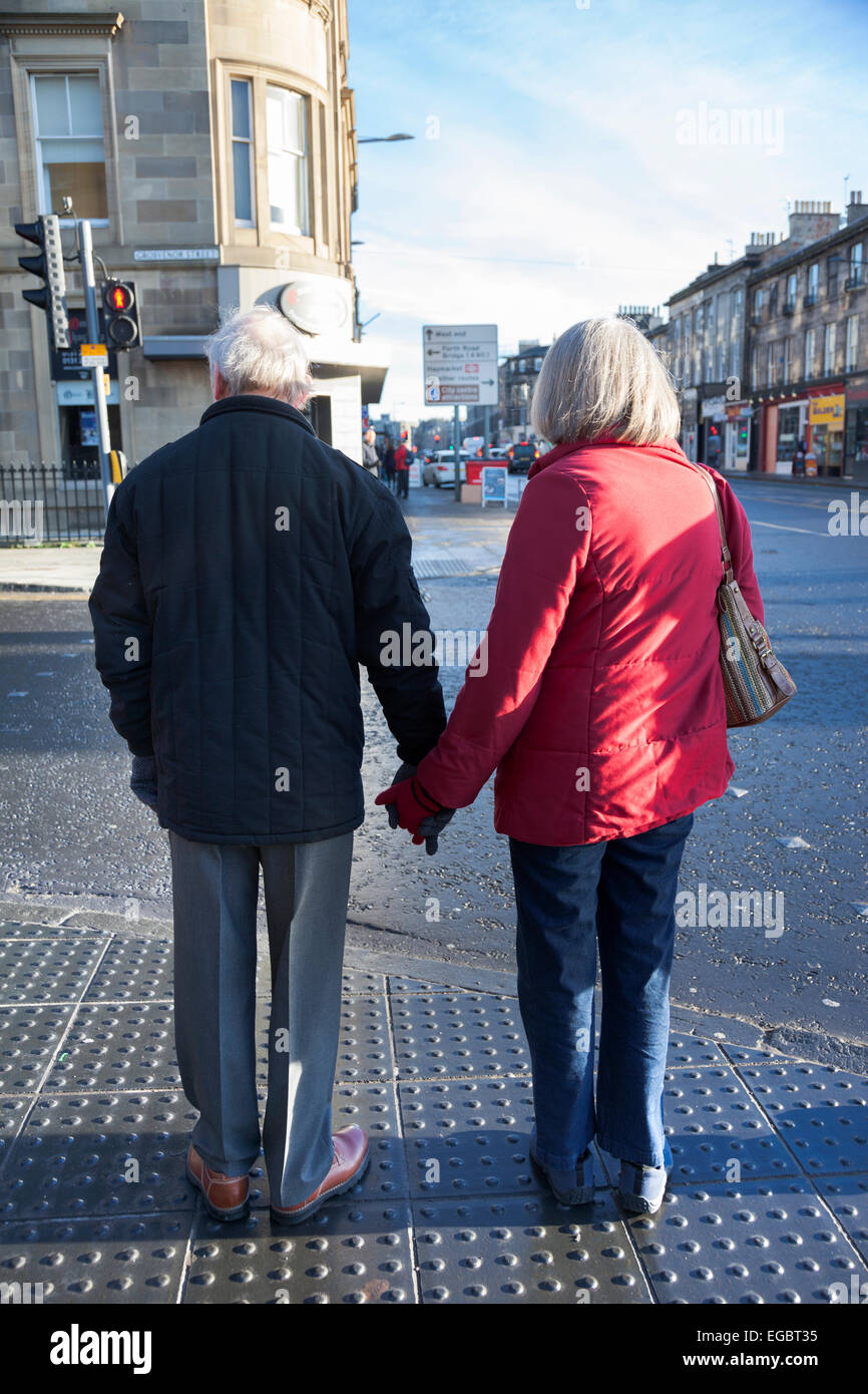 Coppia di anziani tenendo le mani sulle strade di Edimburgo Foto Stock