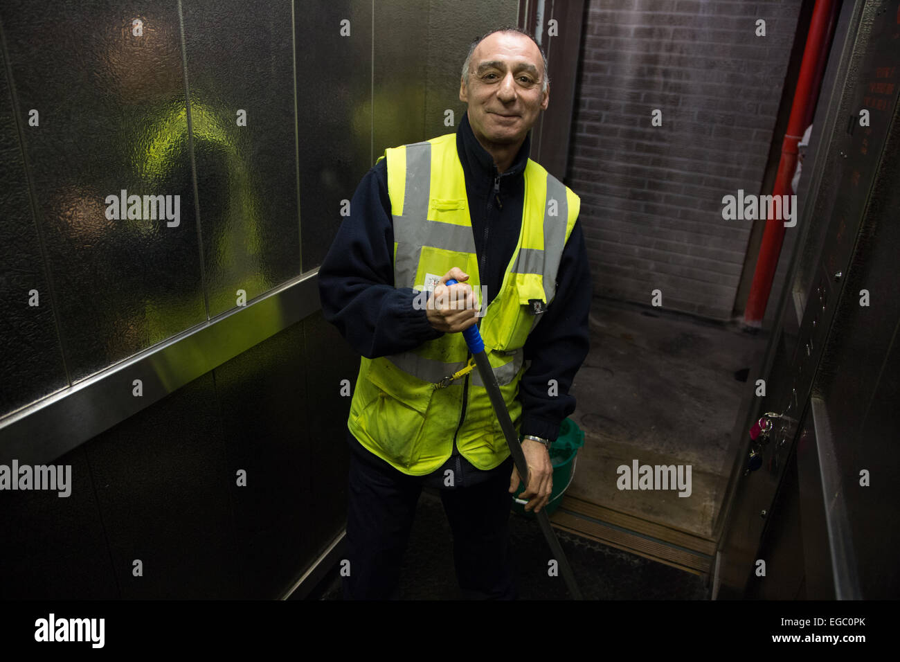 Uomo con straccio il pavimento di un ascensore o un ascensore in un blocco di appartamenti a Londra Foto Stock